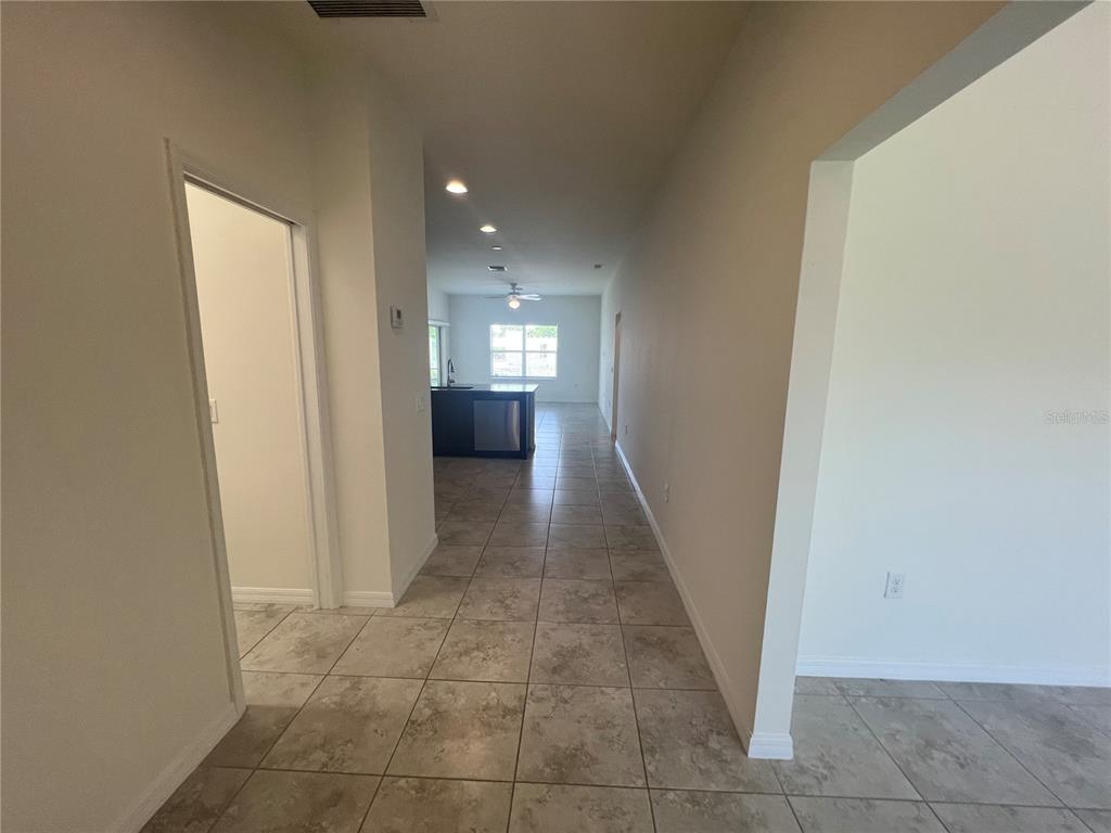 A tiled hallway leads to an open kitchen with a dark island and stainless appliances — 354 ALBATROSS ROAD, ROTONDA WEST, FL