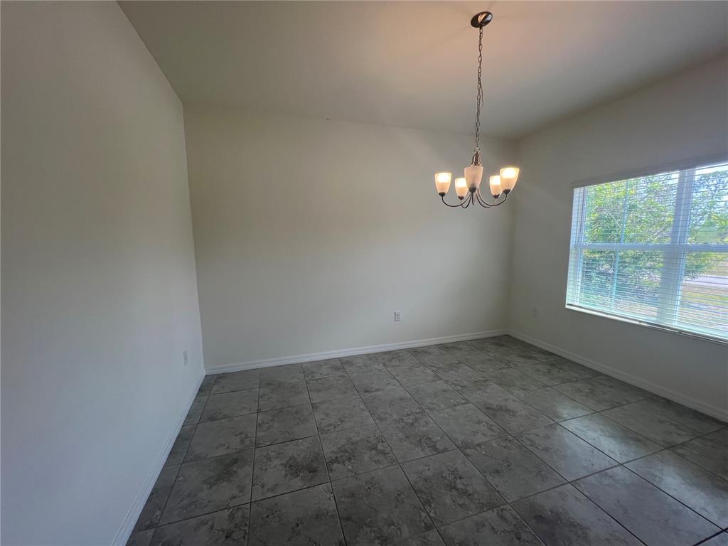 A dining room with grey tile flooring, white walls, and a hanging chandelier — 354 ALBATROSS ROAD, ROTONDA WEST, FL