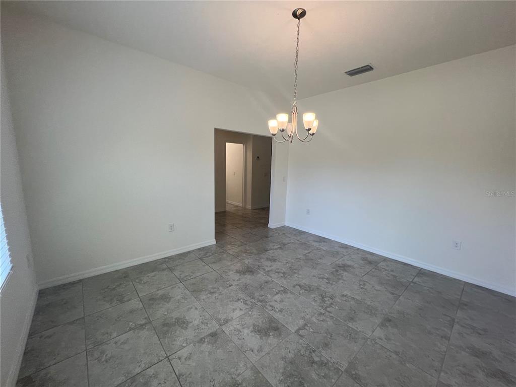 A dining room with gray tile flooring, white walls, and a hanging chandelier — 354 ALBATROSS ROAD, ROTONDA WEST, FL
