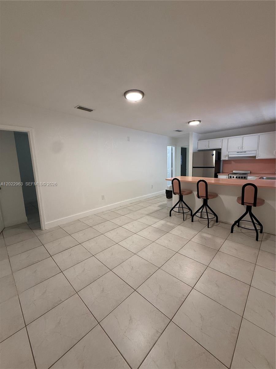A kitchen with white cabinets, a breakfast bar, and light-colored tile flooring — 1046 NW 33rd Ave, Miami FL 33125, MIAMI, FL