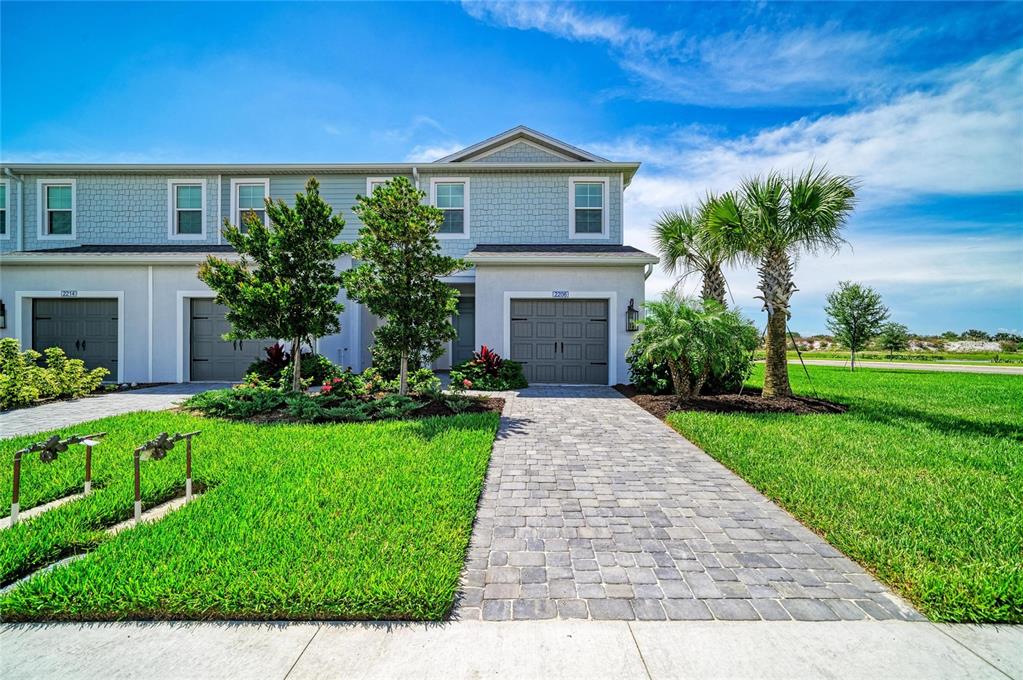 A two-story townhouse with a paved driveway, a garage, and a landscaped front lawn — 2206 WASHINGTON PALM COURT, BRADENTON, FL