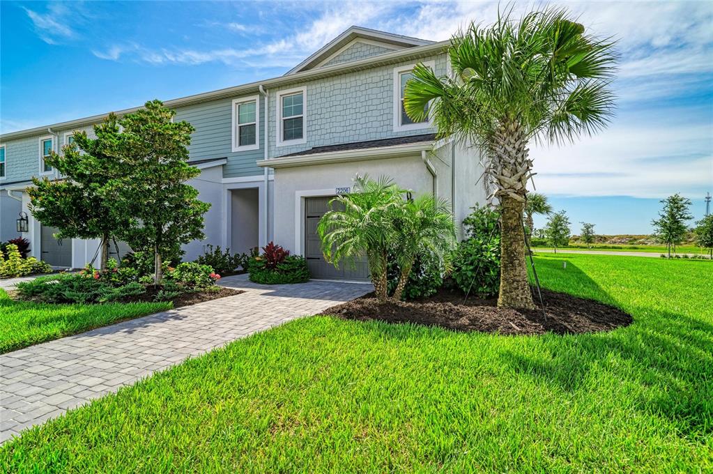 A two-story townhouse exterior with a paved walkway, a palm tree, and green lawn — 2206 WASHINGTON PALM COURT, BRADENTON, FL