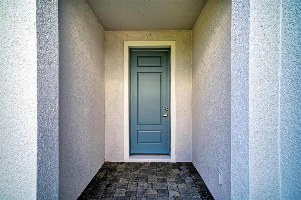 A blue front door is set within a recessed entryway featuring textured walls and pavers — 2206 WASHINGTON PALM COURT, BRADENTON, FL