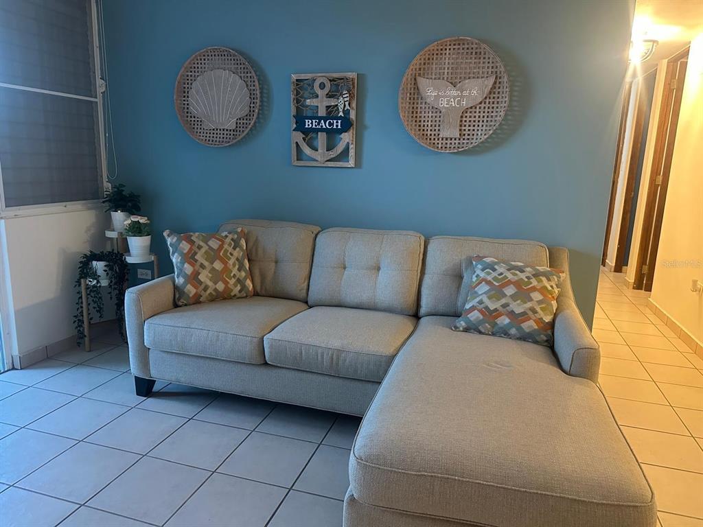 A light blue living room features a gray sectional sofa and coastal-themed wall decor — 1 SUNBAY MARINA VILLAS, FAJARDO, PR
