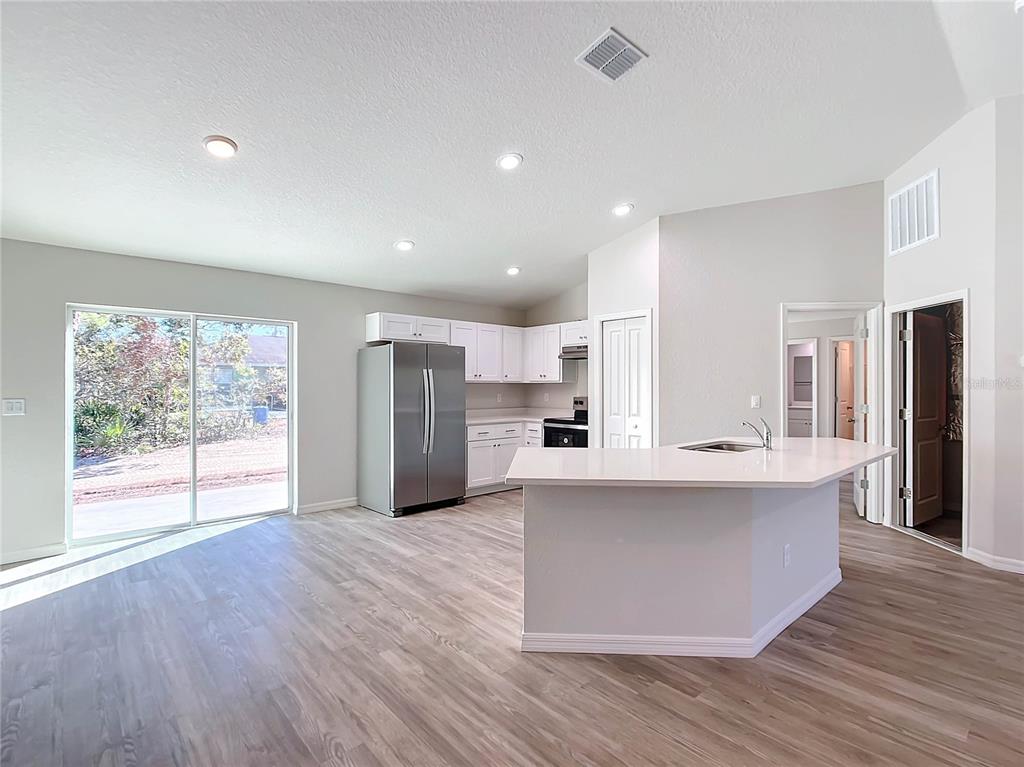 A kitchen with white cabinets, stainless steel appliances, and a central island with a sink — 12063 SE 89TH AVENUE, BELLEVIEW, FL