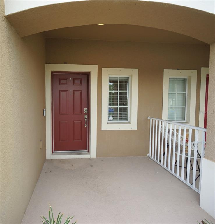 A covered porch features a red front door, two windows, and a white metal railing — 6938 TOWNE LAKE ROAD, RIVERVIEW, FL
