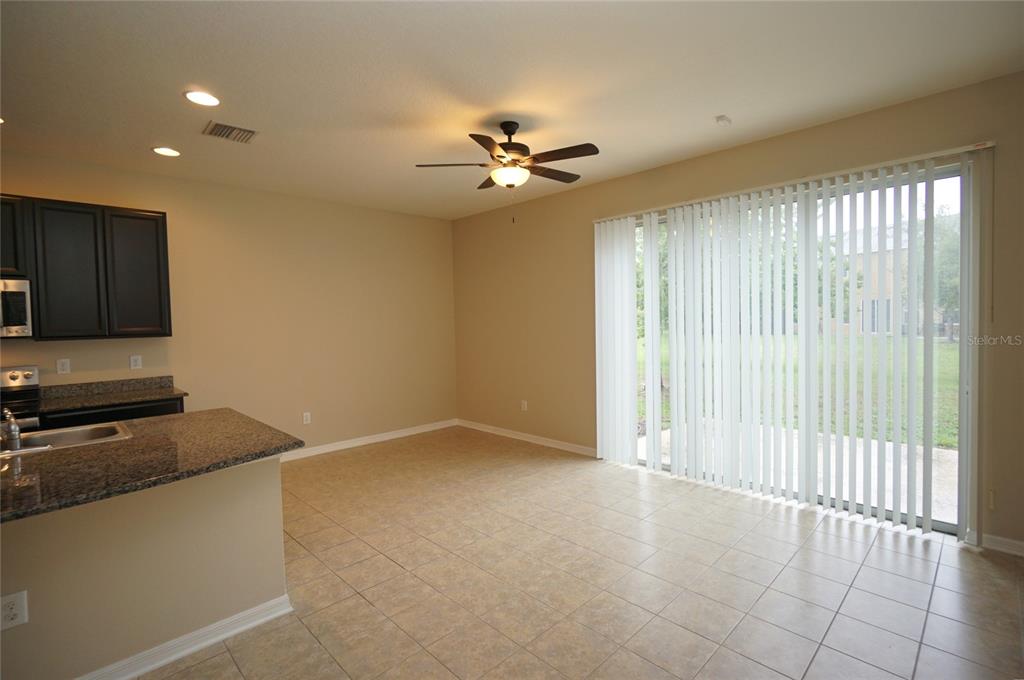 A kitchen with granite countertops and a dining area featuring tile floors and sliding doors — 6938 TOWNE LAKE ROAD, RIVERVIEW, FL