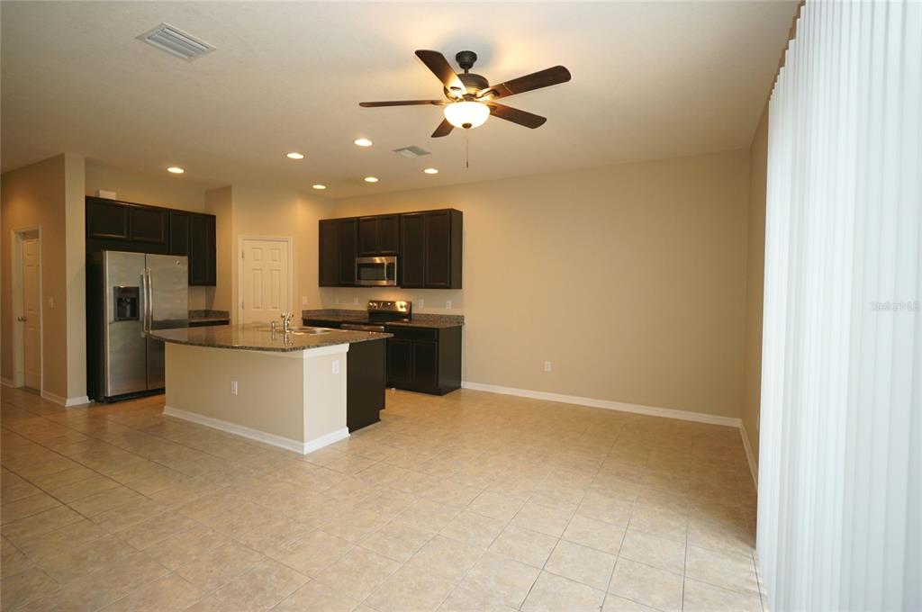 A kitchen with dark cabinets, granite countertops, a center island, and tile flooring — 6938 TOWNE LAKE ROAD, RIVERVIEW, FL