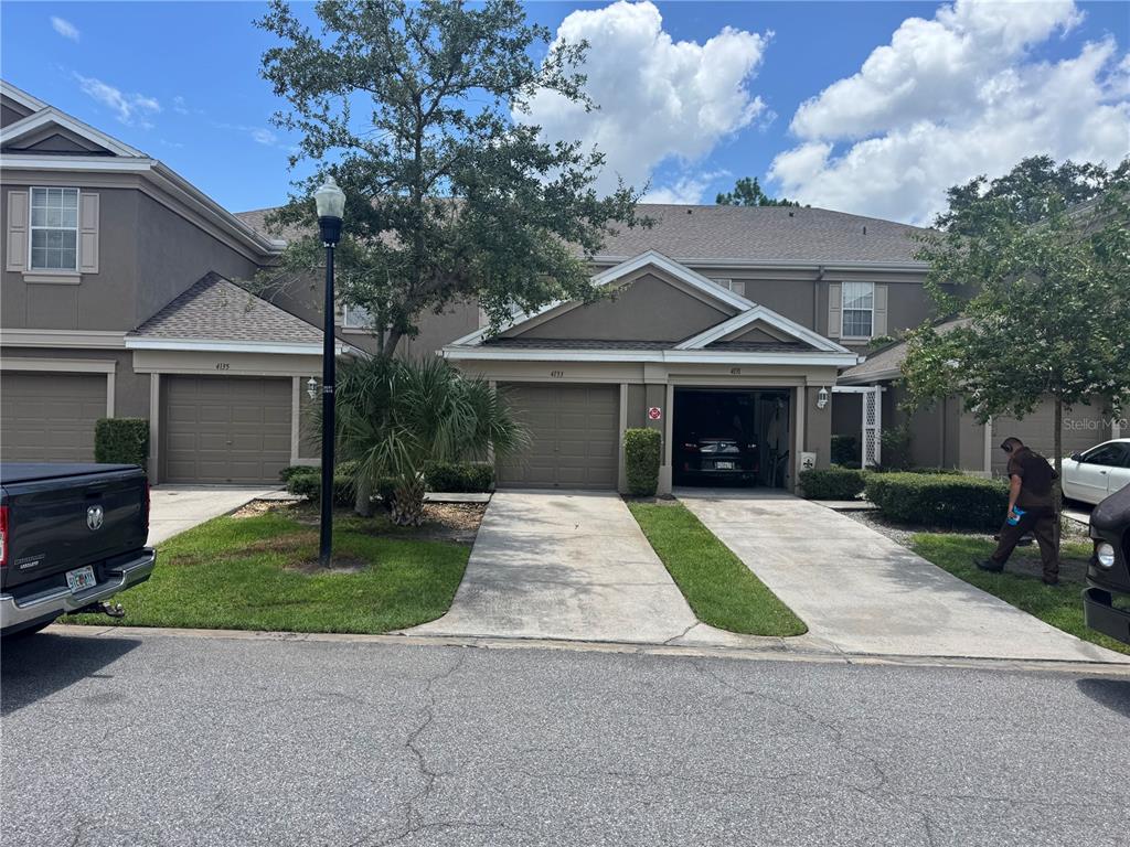 A row of attached townhomes with garages, concrete driveways, and a small front lawn — 4133 KEY THATCH DRIVE, TAMPA, FL