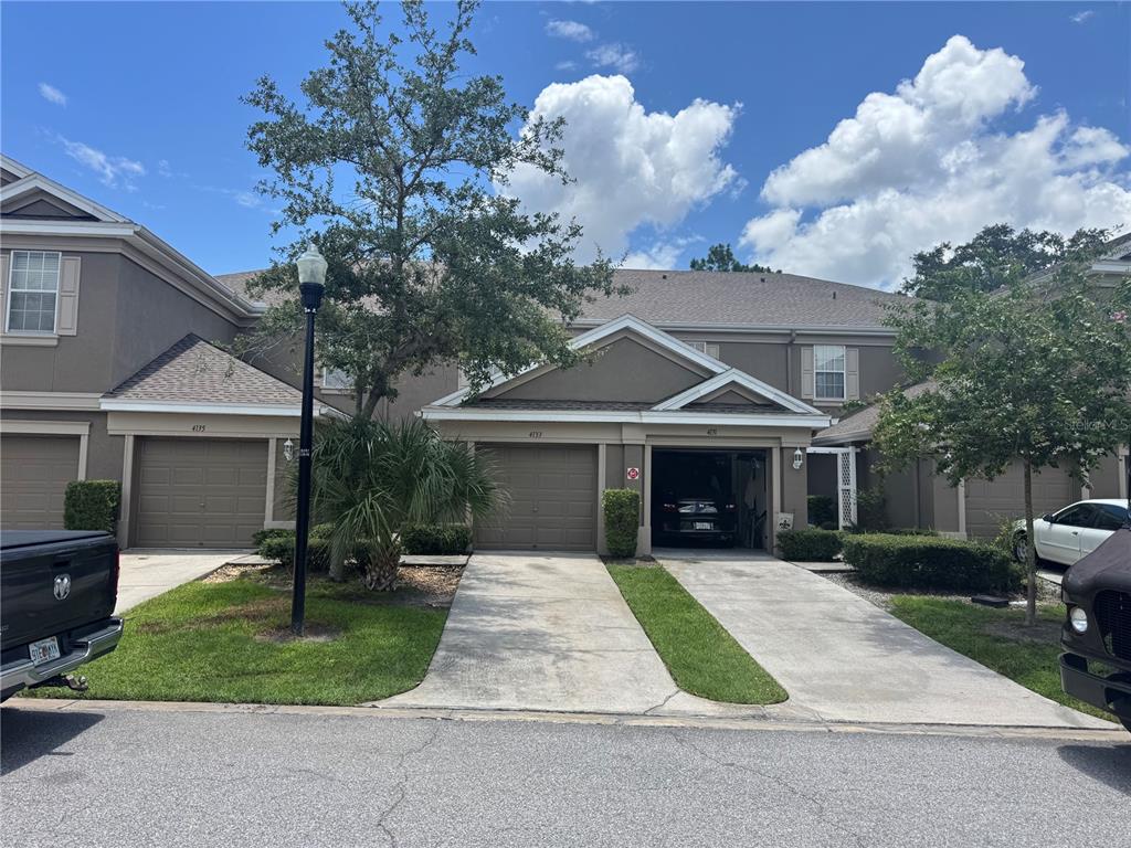 A row of attached townhomes with brown garages, concrete driveways, and a street lamp — 4133 KEY THATCH DRIVE, TAMPA, FL