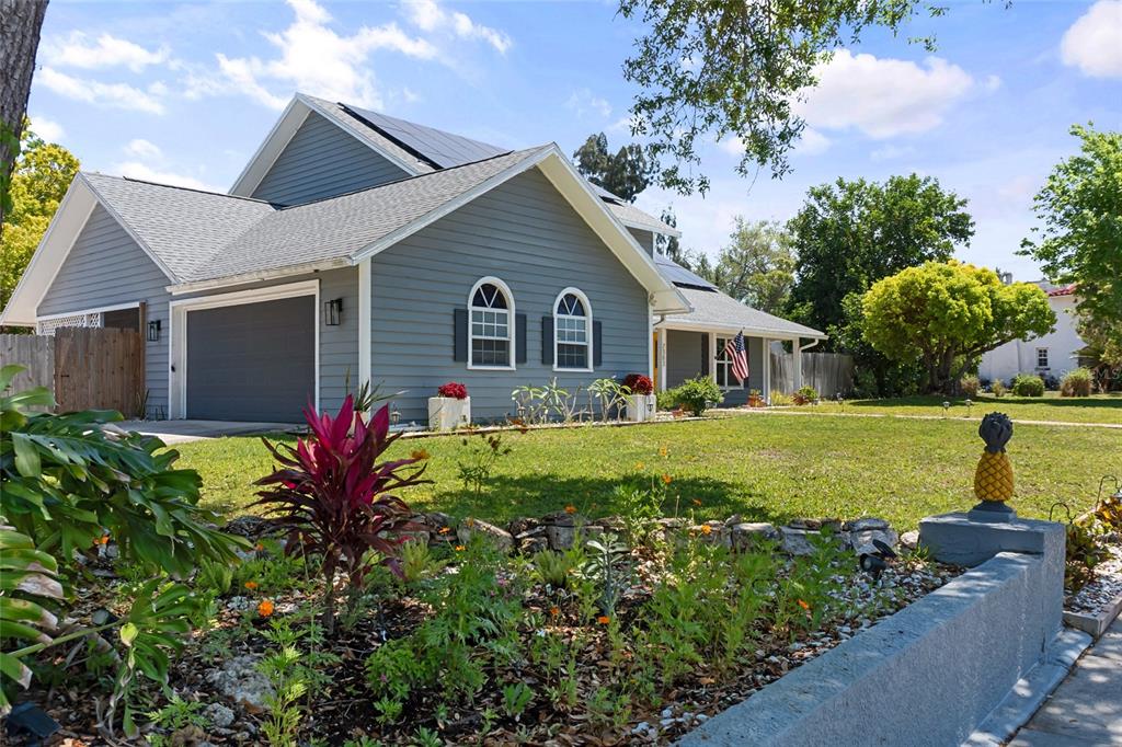 A gray house with a garage and a front garden featuring a pineapple-shaped statue — 7303 MANATEE STREET, SARASOTA, FL