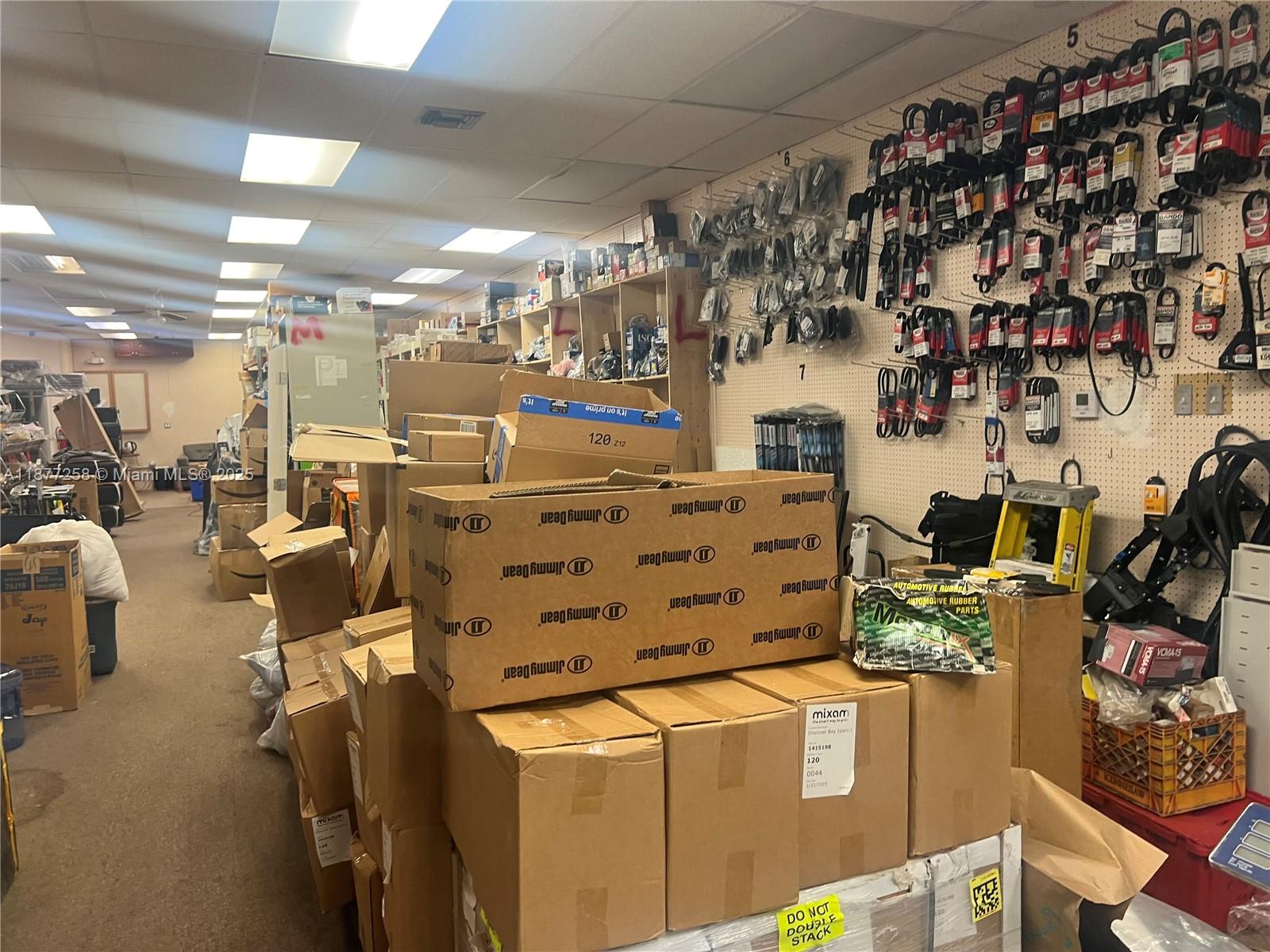 This commercial storage room features shelves, pegboard walls with hanging inventory, and numerous cardboard boxes — LAUDERDALE LAKES, FL