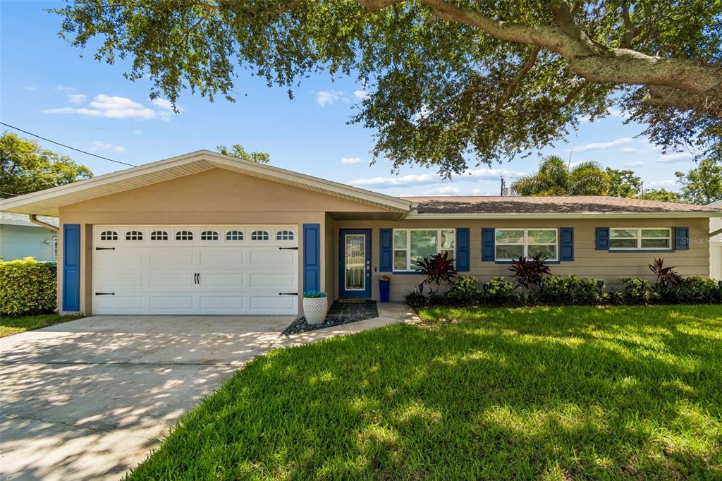 A single-story house with a white garage door, blue shutters, and a large oak tree — 9045 RIDGE ROAD, SEMINOLE, FL