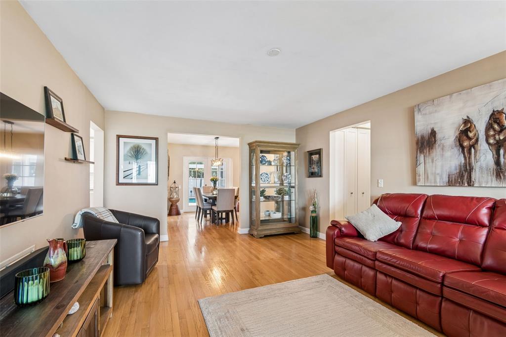 A living room with hardwood floors, a red leather sofa, and an adjacent dining area — 9045 RIDGE ROAD, SEMINOLE, FL