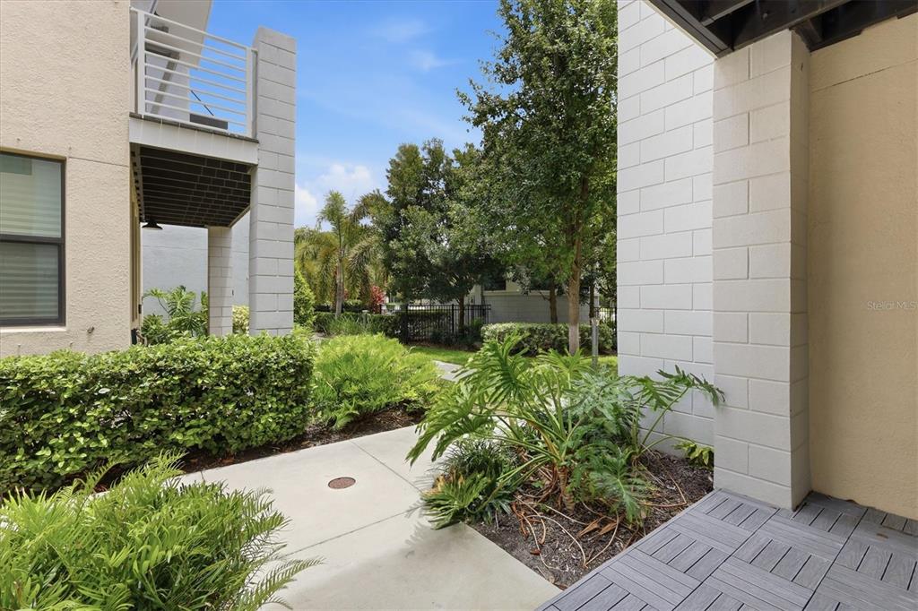 A concrete walkway leads between two modern buildings with landscaped shrubs and a patio area — 2551 11TH PL N, ST PETERSBURG, FL