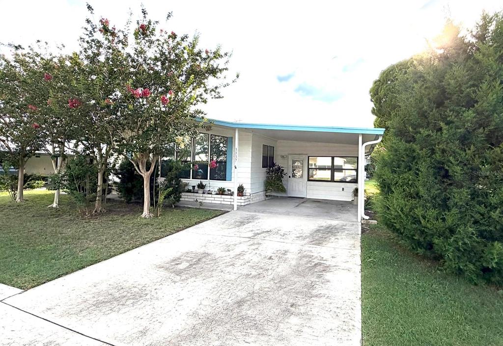 A single-story mobile home features a white exterior, a carport, and a concrete driveway — 3937 CHRIS DRIVE, WESLEY CHAPEL, FL