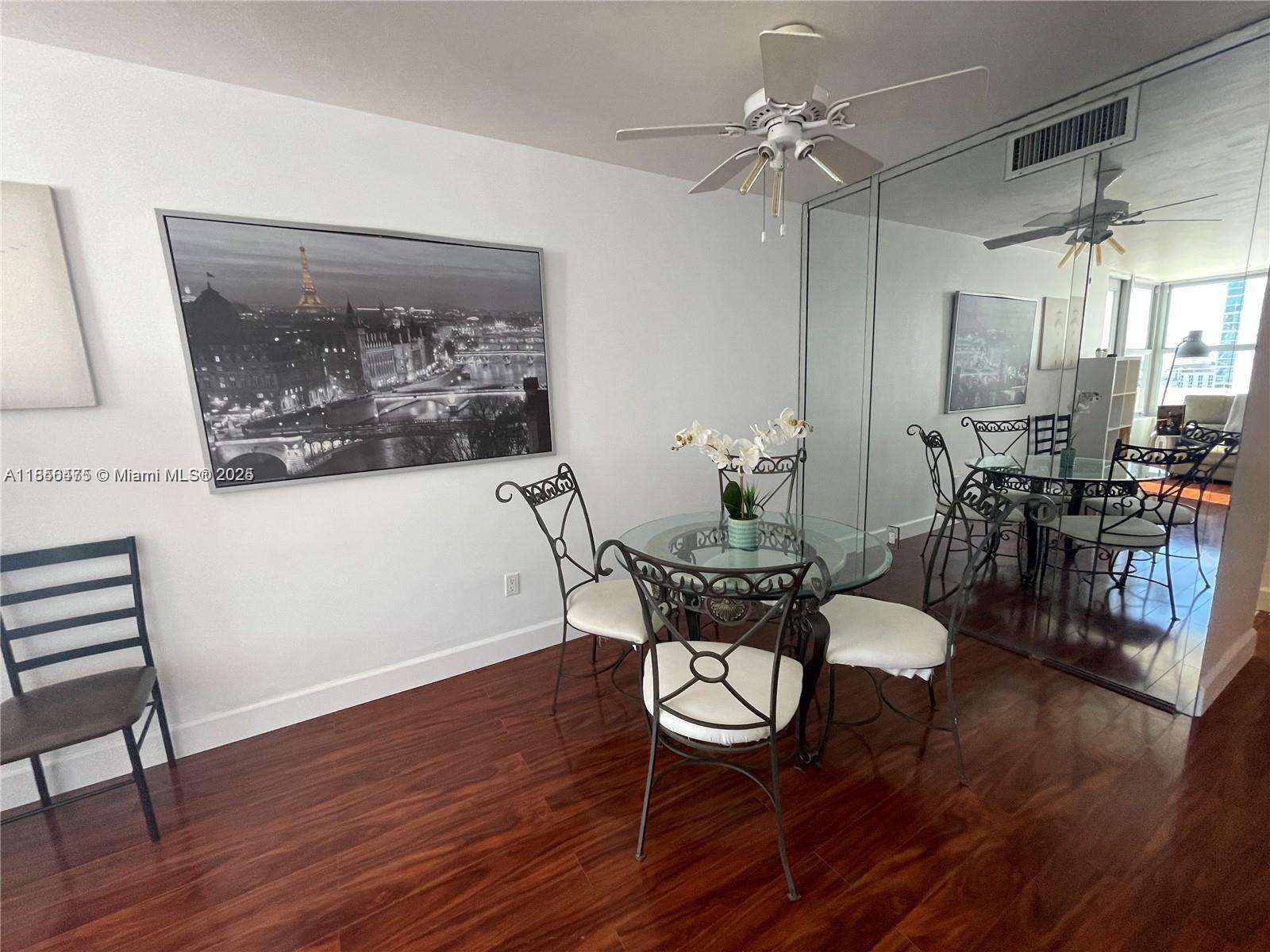 A dining area features a glass table, metal chairs, hardwood floors, and a mirrored wall — 2899 Collins Ave # 1420, Miami Beach FL 33140, MIAMI BEACH, FL