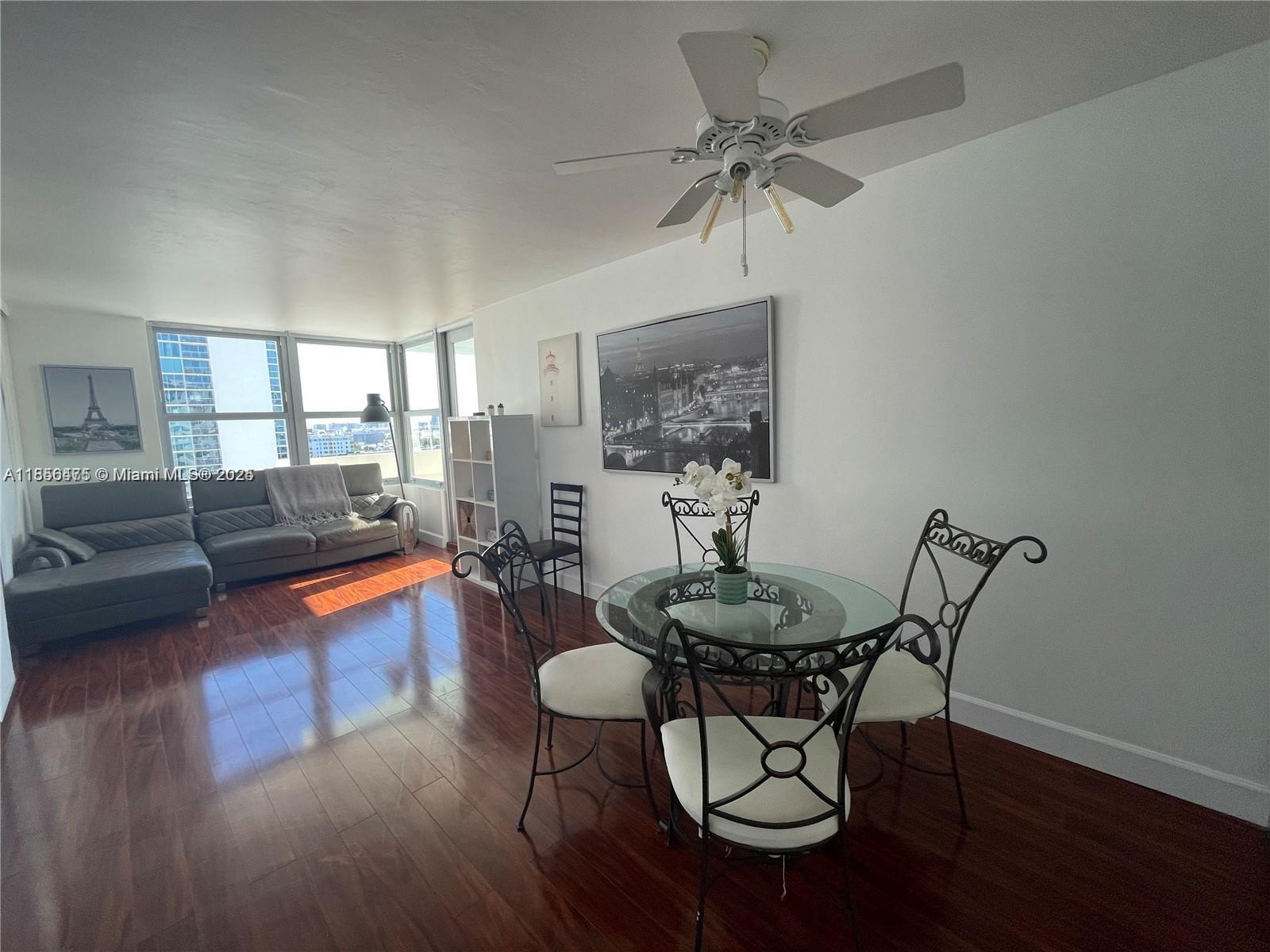 A living and dining area features dark wood floors, a glass-top table, and city views — 2899 Collins Ave # 1420, Miami Beach FL 33140, MIAMI BEACH, FL