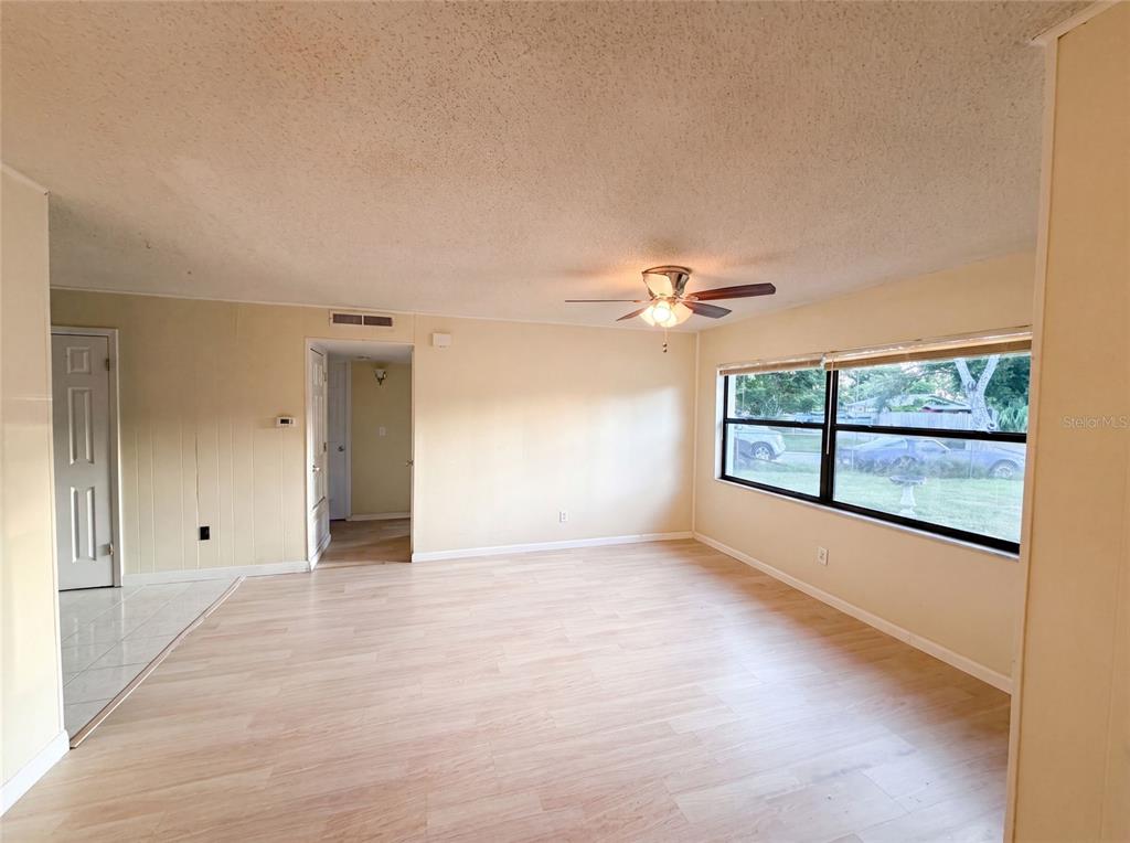 A living room with light-colored wood flooring, pale yellow walls, and a ceiling fan — 722 VIRGINIA LANE, APOPKA, FL