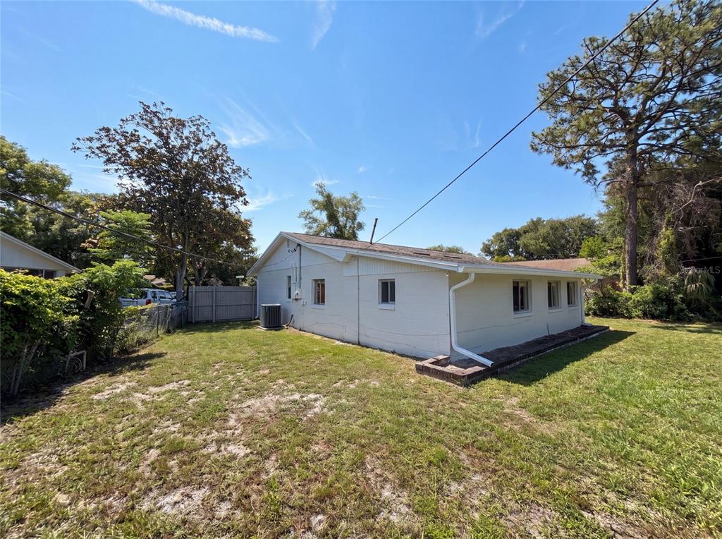 The exterior of a white, single-story house features a grassy yard and a central AC unit — 722 VIRGINIA LANE, APOPKA, FL