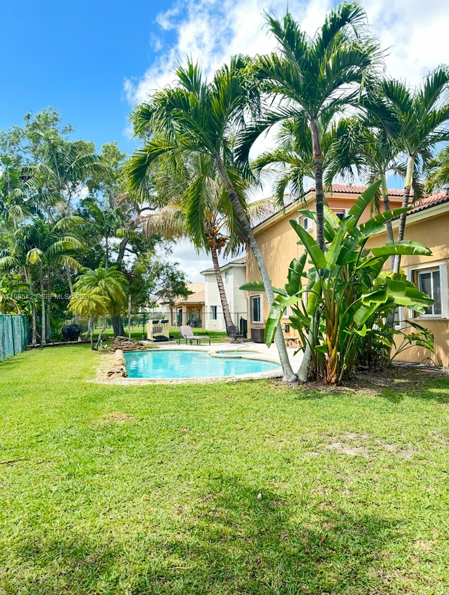 A backyard features a swimming pool, palm trees, and a tan house exterior — 1958 SE 23rd Ct, Homestead FL 33035, HOMESTEAD, FL