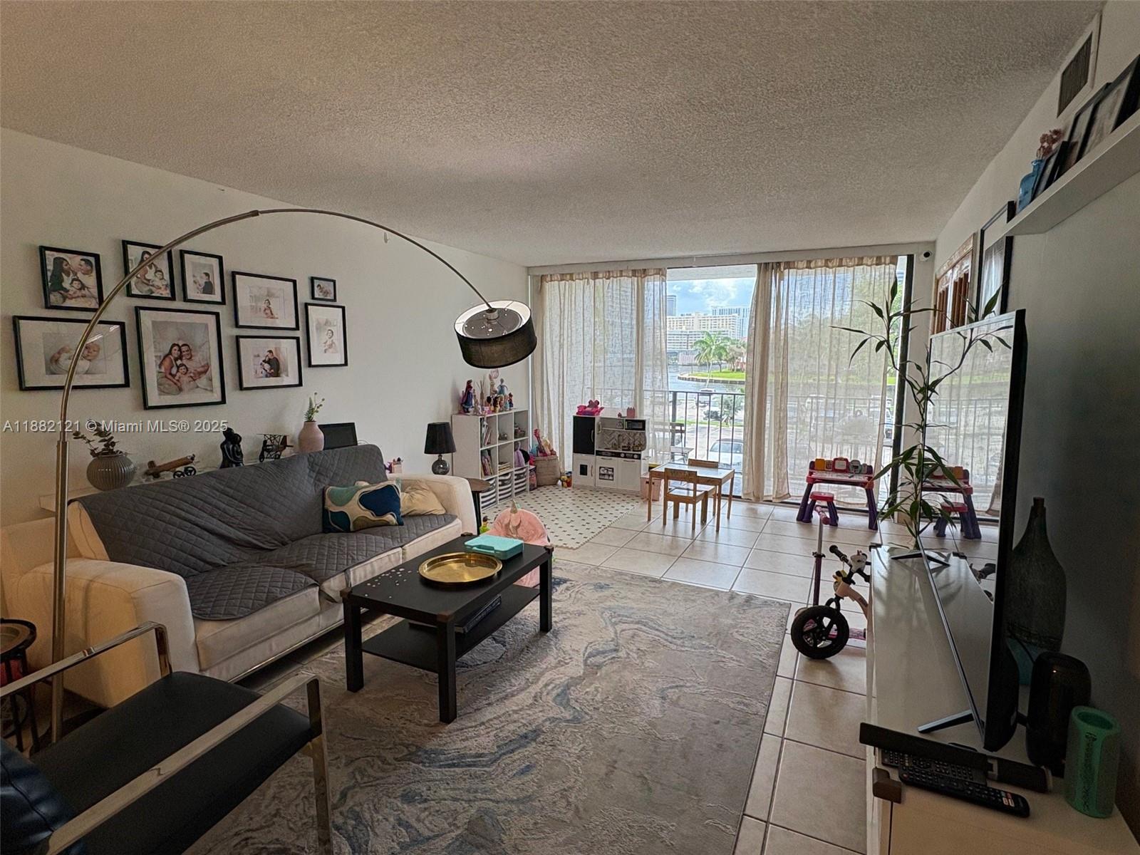A living room features a sofa, a coffee table, a rug, and a balcony view — 200 Leslie Dr # 228, Hallandale Beach FL 33009, HALLANDALE BEACH, FL