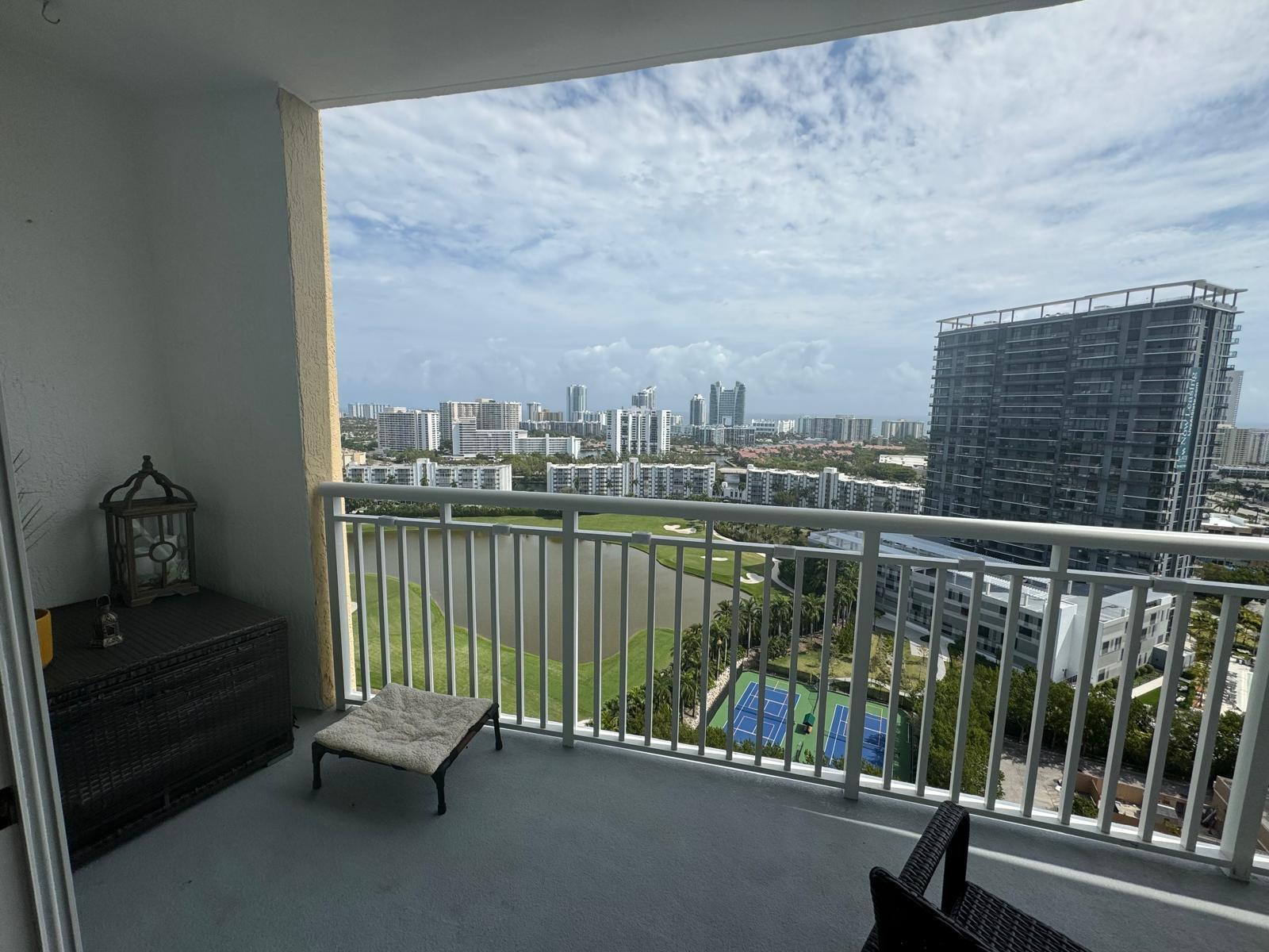 A balcony overlooks a lake, tennis courts, and a city skyline under a cloudy sky — 1755 E Hallandale Beach Boulevard # 2104e, FL 33009, FL
