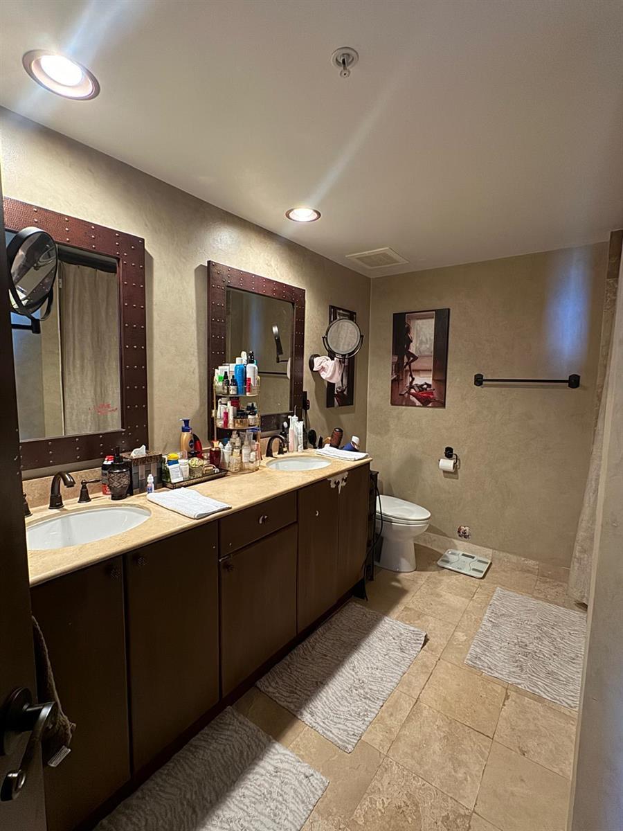 A bathroom features a double vanity with dark cabinets, framed mirrors, and beige tile flooring — 1755 E Hallandale Beach Boulevard # 2104e, FL 33009, FL