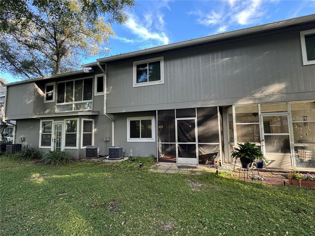 The exterior of a two-story gray house features a screened-in porch and two air-conditioning units — 626 RED OAK CIRCLE UNIT 110, ALTAMONTE SPRINGS, FL