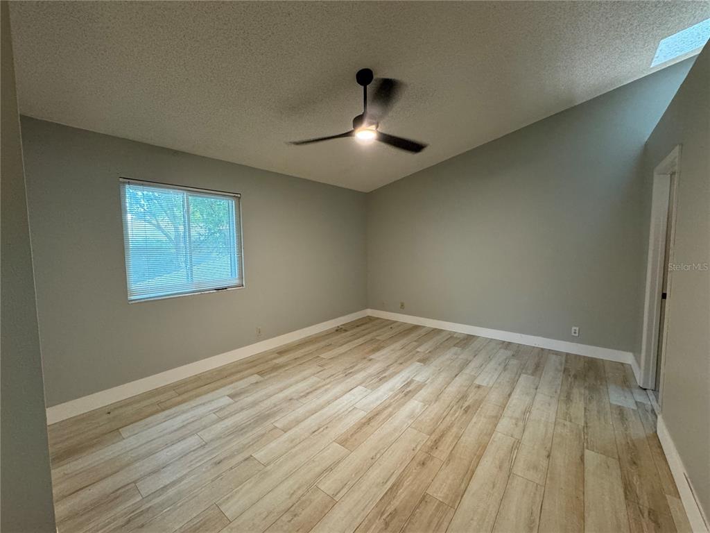 This bedroom features light wood-look tile flooring, gray walls, and a vaulted ceiling — 626 RED OAK CIRCLE UNIT 110, ALTAMONTE SPRINGS, FL