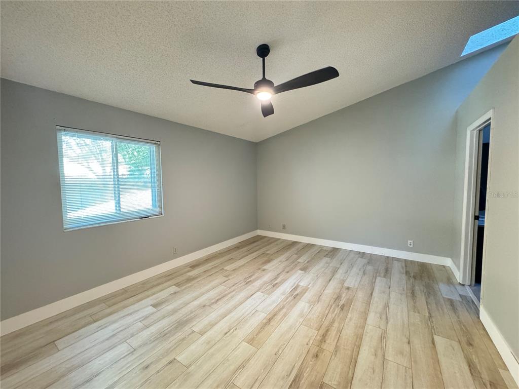 An empty bedroom features light wood-look flooring, gray walls, a ceiling fan, and a skylight — 626 RED OAK CIRCLE UNIT 110, ALTAMONTE SPRINGS, FL