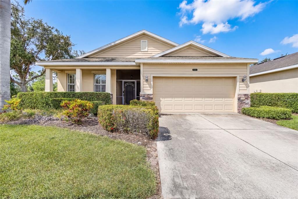 A single-story house with beige siding, a two-car garage, and a manicured front lawn — 8531 KARPEAL DRIVE, SARASOTA, FL