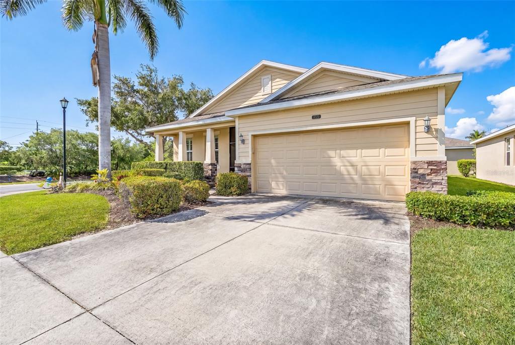 A single-story house with tan siding, a stone facade, and a two-car garage — 8531 KARPEAL DRIVE, SARASOTA, FL