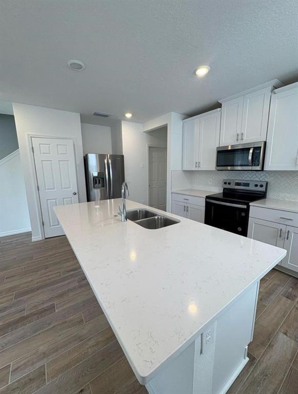A modern kitchen features white cabinets, a large quartz island, and stainless steel appliances — 16407 BIRD OF PARADISE AVENUE, CLERMONT, FL