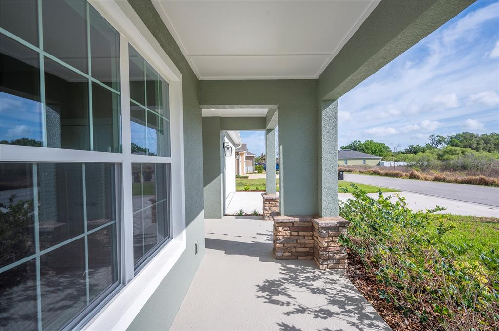The exterior of a house features a covered entryway with stone-based columns and a door — 4537 FAIRWAY OAKS DRIVE, MULBERRY, FL