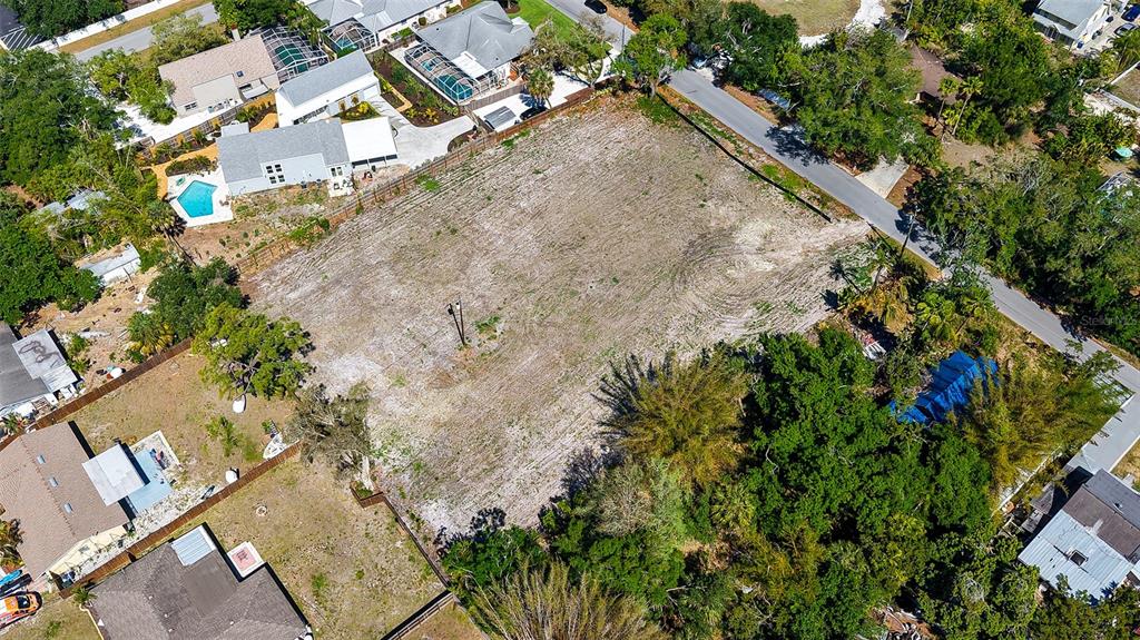 An aerial view shows a cleared, rectangular vacant lot surrounded by residential houses and trees — 2424 ASHTON ROAD, SARASOTA, FL