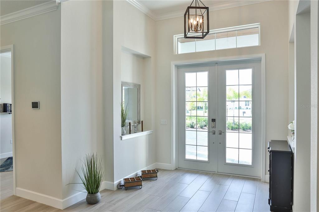 A bright entryway features light wood-look tile floors, a lantern pendant light, and double doors — 2424 ASHTON ROAD, SARASOTA, FL