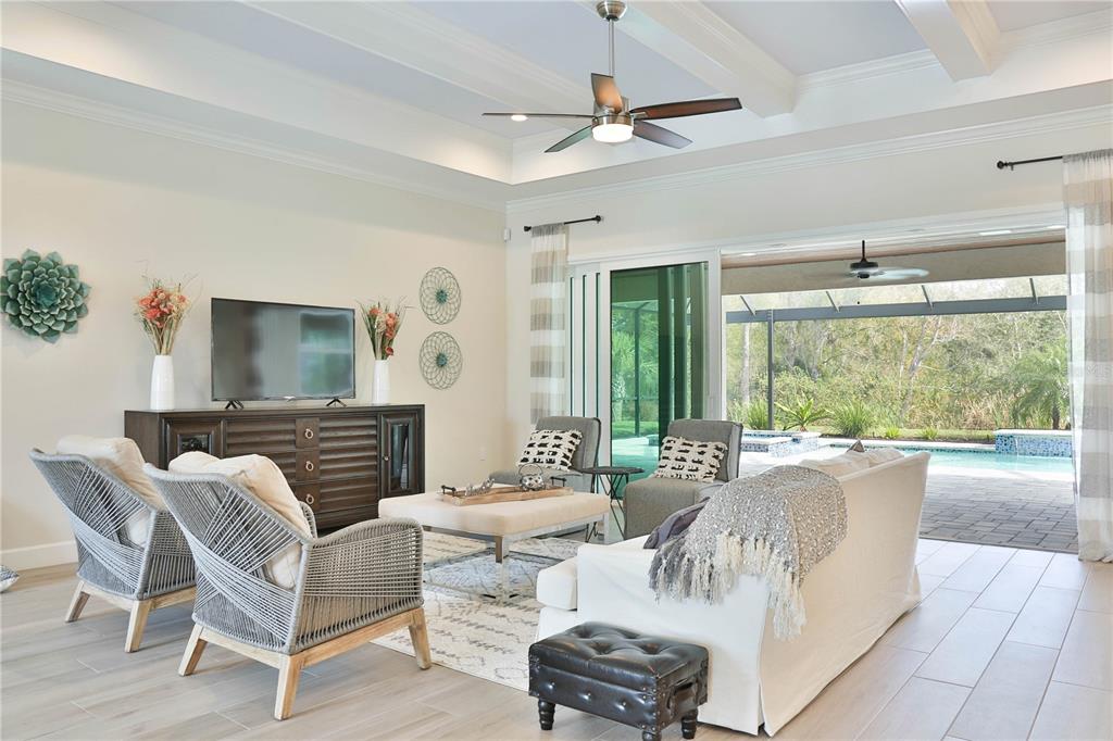 A living room features a tray ceiling, sliding glass doors, and a view of a pool — 2424 ASHTON ROAD, SARASOTA, FL