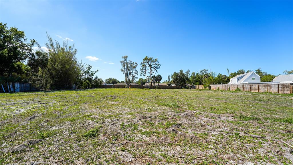 A large, flat, vacant grassy lot with scattered trees and a wooden fence in back — 2424 ASHTON ROAD, SARASOTA, FL