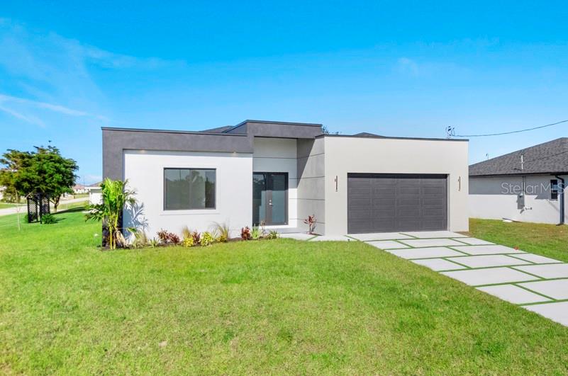A modern single-story house with a flat roof, gray stucco exterior, and a paved driveway — 3927 NW 38TH STREET, CAPE CORAL, FL