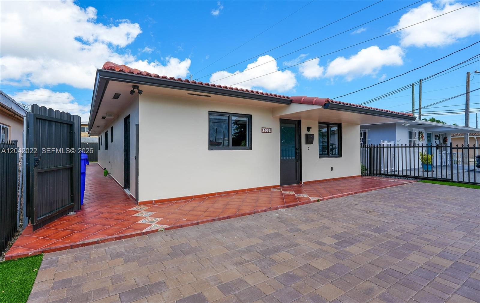 A single-story house with a tiled roof, beige stucco walls, and a paved driveway — 509 NW 57th Ct, Miami FL 33126, MIAMI, FL