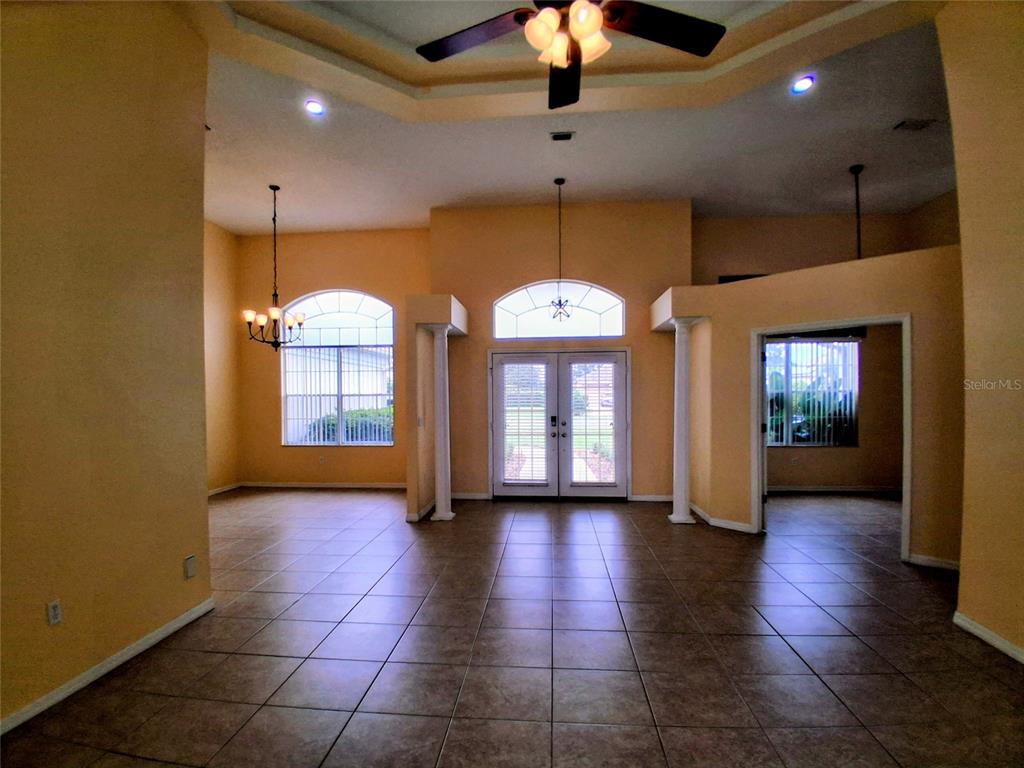 A spacious room with tile flooring, high ceilings, a ceiling fan, and double glass doors — 3392 ST IVES BOULEVARD, SPRING HILL, FL