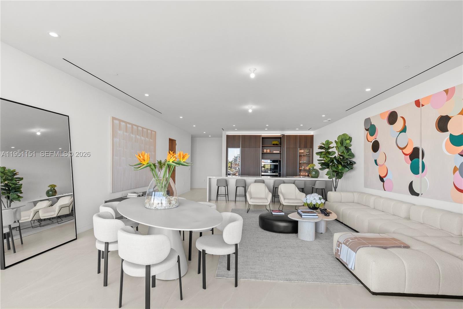 A modern open-concept living and dining area features white furniture, neutral decor, and kitchen cabinetry — 5 Grove Isle # S301, Coconut Grove FL 33133, COCONUT GROVE, FL