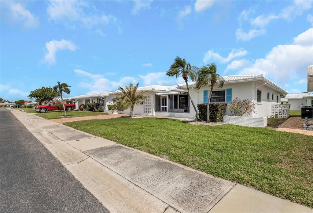 A white single-story house with a lawn, palm trees, and a red truck parked outside — 3627 100TH PLACE N UNIT 4, PINELLAS PARK, FL