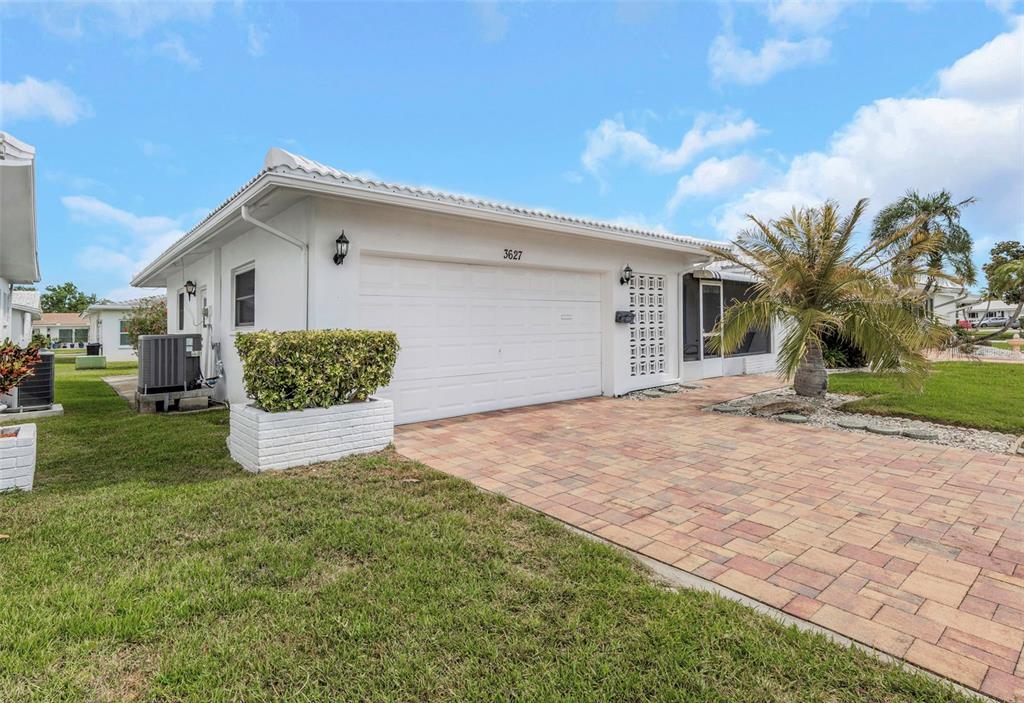 A white single-story house with a paved driveway, a two-car garage, and a palm tree — 3627 100TH PLACE N UNIT 4, PINELLAS PARK, FL