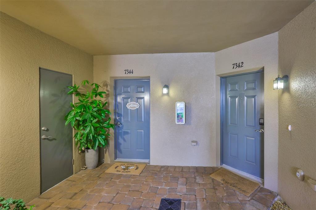 A covered entryway features two blue doors with house numbers and a paved floor — 7344 SKYBIRD ROAD, BRADENTON, FL