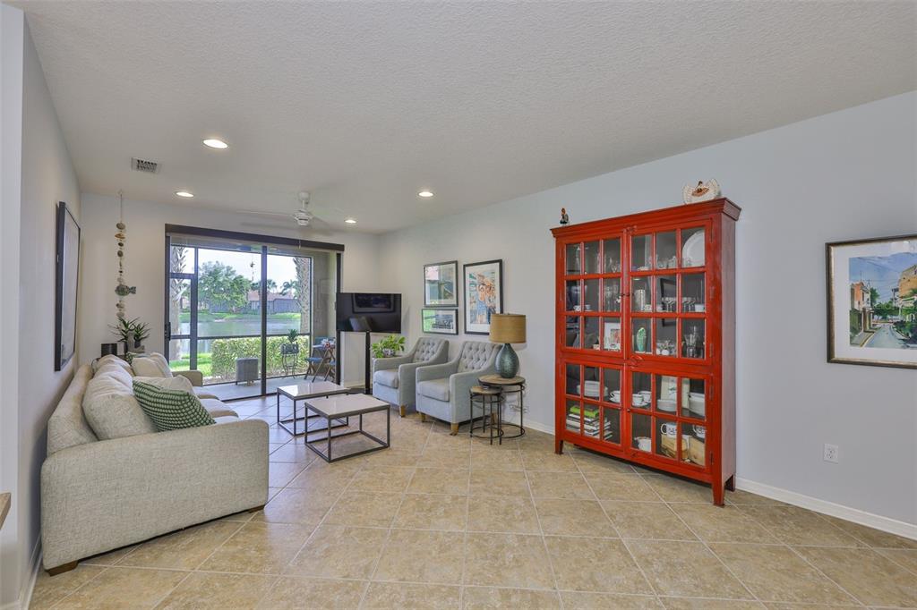 A living room features tile floors, a red display cabinet, and sliding doors to a patio — 7344 SKYBIRD ROAD, BRADENTON, FL
