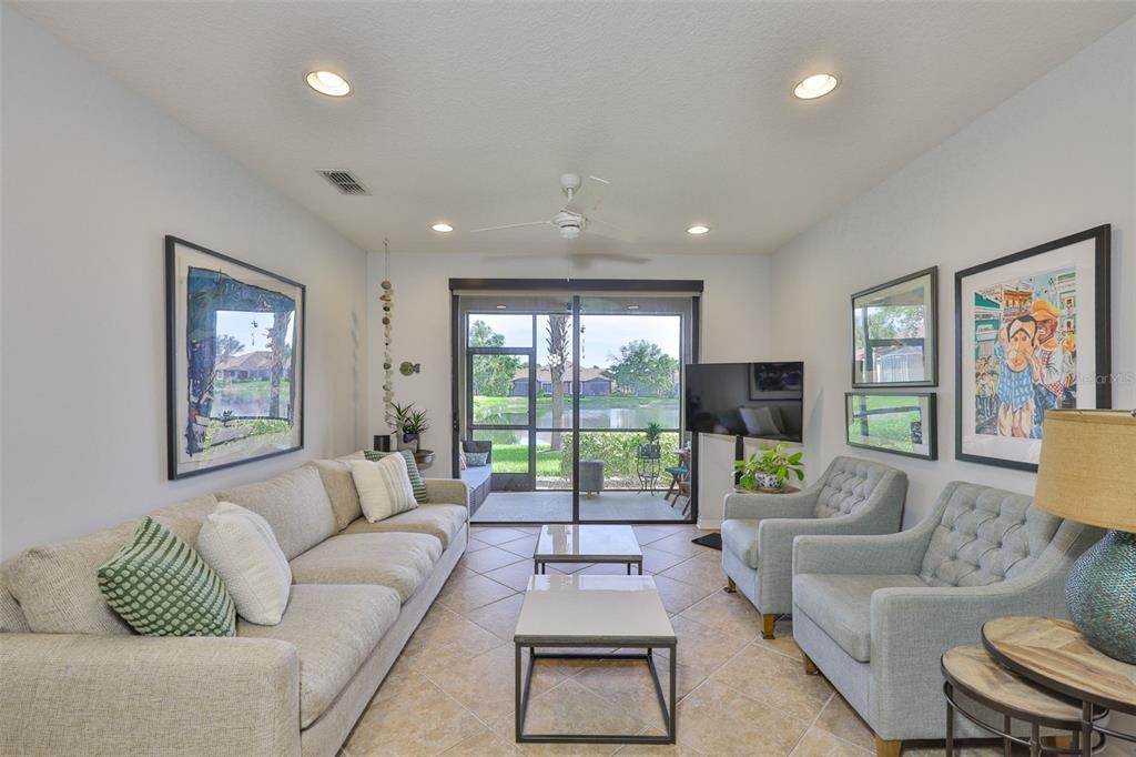 A living room with a sofa, two armchairs, a coffee table, and a screened-in patio — 7344 SKYBIRD ROAD, BRADENTON, FL