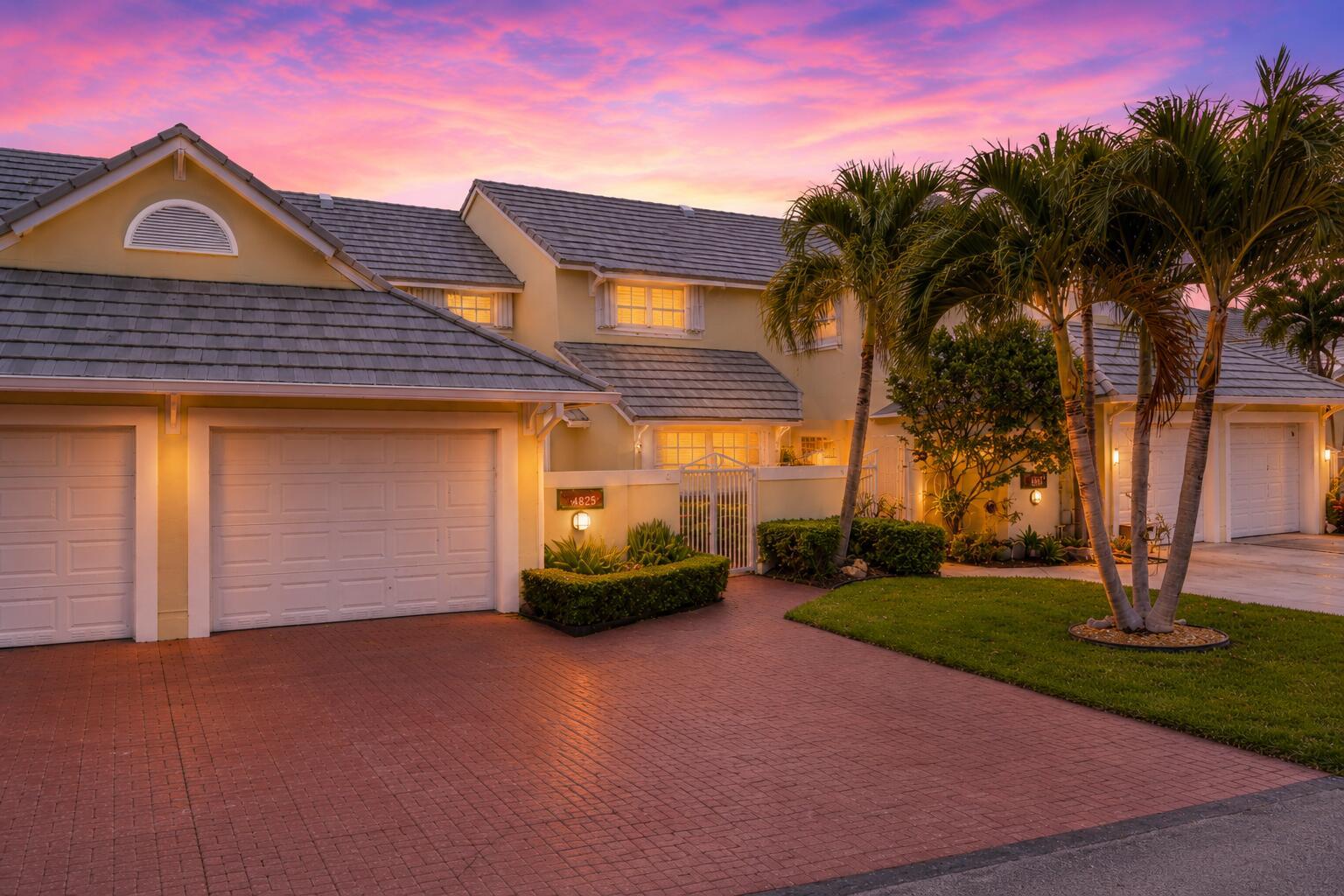 A two-story house with a brick driveway, two garage doors, and palm trees at sunset — 4825 NW 98th Place, Doral FL 33178, DORAL, FL