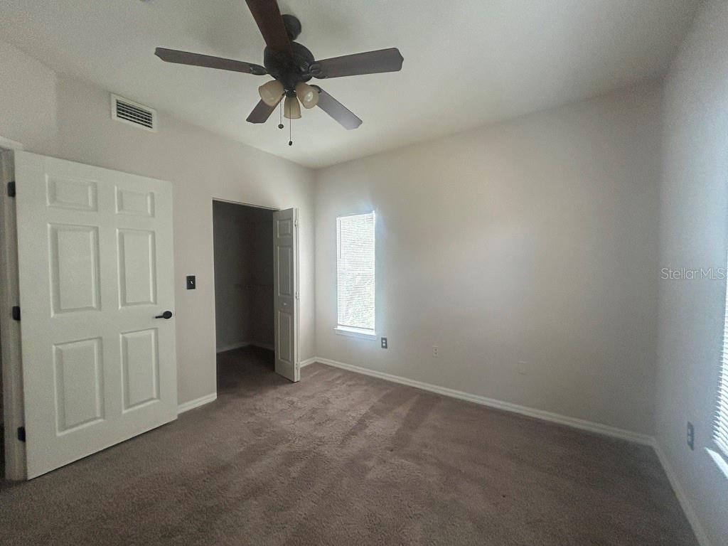 A bedroom with beige carpet, a ceiling fan, and an open closet door — 5616 PINNACLE HEIGHTS CIRCLE UNIT 308, TAMPA, FL